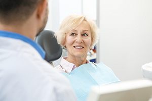 older woman smiling while looking at dentist 