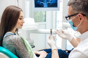 A dentist shows a young female patient how an implant works during a consultation