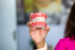 Woman holding dentures at dental office