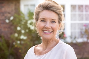 An older woman smiling outside.