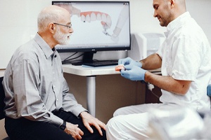 Dentist showing an older patient dentures in Collierville.
