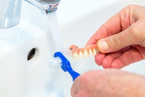 A person cleaning a denture.