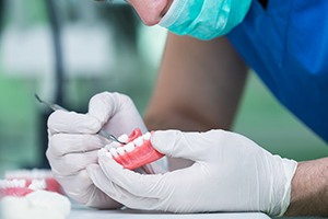 Technician with white gloves sculpting a set of dentures