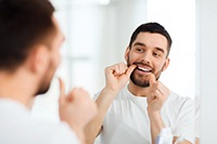 Man flossing his teeth in bathroom
