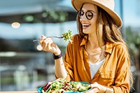 Woman smiling while eating salad outside