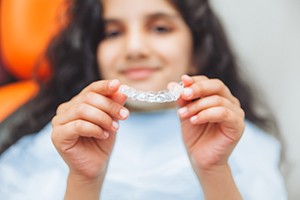 Teen girl smiling while holding clear aligner