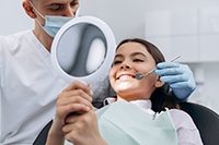 Teen girl smiling at reflection in handheld mirror