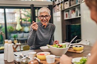 Woman smiling while eating meal with friend at home