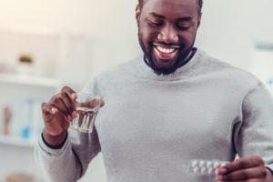 person with a pill in their hand and a glass of water in their other hand