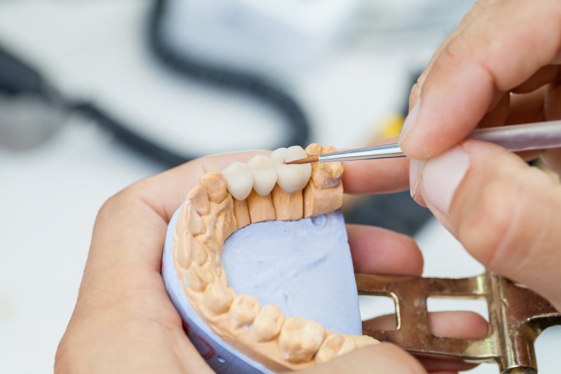 A dental lab technician putting the finishing touches on a dental crown