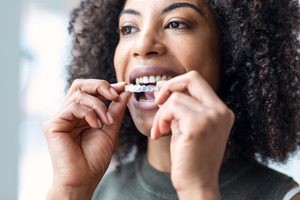 Woman taking Invisalign aligner out of mouth