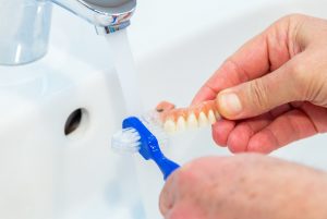 Man cleaning dentures in sink