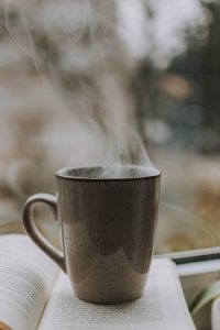 Steaming cup of coffee on book