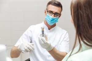 Dentist holding a dental implant model