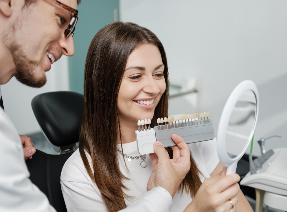 Dentist holding veneers up for patient in chair