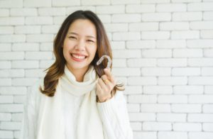 Woman during the holidays holding a clear aligner.